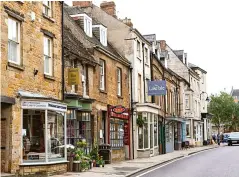  ??  ?? The Rutland market town of Uppingham (left). Cushions in the bedroom (below left) are from Anthropolo­gie. Below: Nadia on her Heal’s sofa. Opposite: flower borders outside All Saints Church in Oakham