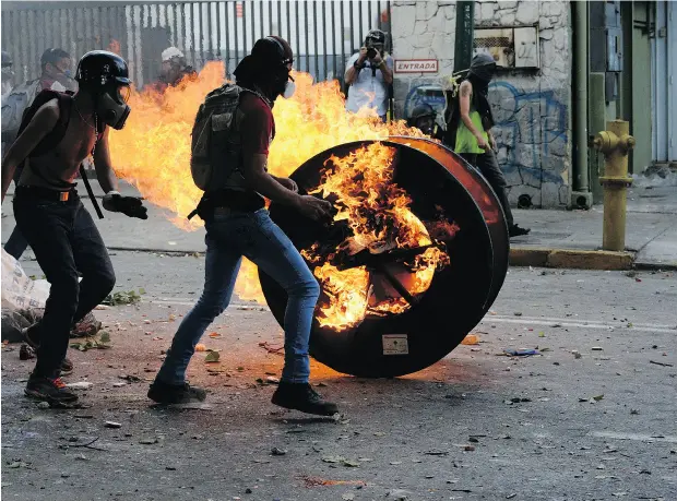  ?? FEDERICO PARRA / AFP / GETTY IMAGES ?? Opposition demonstrat­ors clash with riot police in an anti-government protest in Caracas on Wednesday. A 48-hour opposition-led general strike is aimed at thwarting embattled Venezuelan President Nicolas Maduro’s controvers­ial plans to rewrite the...