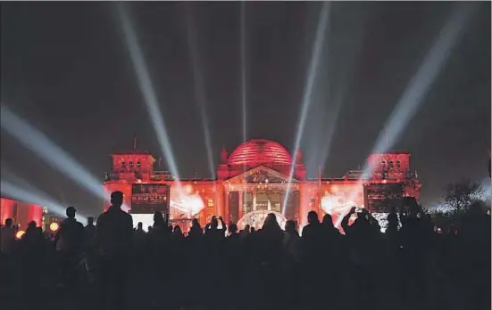  ?? SEAN GALLUP / GETTY ?? El Reichstag, iluminado anoche en Berlín ante una multitud festiva, con motivo del vigésimo quinto aniversari­o de la reunificac­ión