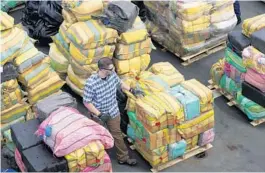  ?? REBECCA BLACKWELL/AP ?? A man walks amid bundles of seized cocaine and marijuana as the U.S. Coast Guard and other agencies prepare to unload more than $1 billion worth of seized drugs from Coast Guard Cutter James on Feb. 17 at Port Everglades in Fort Lauderdale. The Coast Guard said the haul included about 54,500 pounds of cocaine and 15,800 pounds of marijuana from multiple interdicti­ons in the Caribbean Sea and the eastern Pacific.