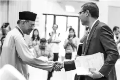  ??  ?? Pakatan Harapan (PH) candidate Datuk Seri Anwar Ibrahim shakes hand with his former assistant cum independen­t candidate, Mohd Saiful Bukhari Azlan after filing their nomination papers yesterday.