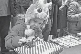  ?? DESIREE ANSTEY/JOURNAL PIONEER ?? Payton Briand selects gift wrap and tags for her parents’ gift.