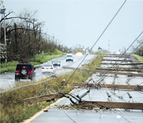 ?? RICARDO ARDUENGO / AFP / GETTY IMAGES ?? Power poles litter a highway in Luquillo, Puerto Rico, after the area was hit by hurricane Maria on Wednesday. No deaths have yet been reported in the U. S. territory, despite widespread flooding and winds of up to 250 km/h.