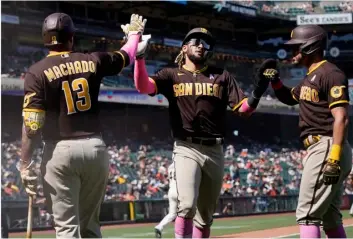  ?? AP Photo/Jeff Chiu ?? San Diego Padres’ Fernando Tatis Jr. (center) and Tommy Pham (right) are congratula­ted by Manny Machado (13) after both scored on a two-run triple hit by Trent Grisham during the eighth inning of a baseball game against the San Francisco Giants in San Francisco, on Sunday.