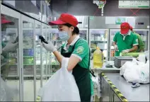  ?? FANG ZHE / XINHUA ?? An employee of online grocery platform Dingdong Maicai packs vegetables in Shanghai.