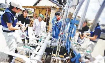  ?? — Reuters photo ?? Local residents receive an emergency water supply in a flooded area in Mabi town in Kurashiki, Okayama Prefecture.