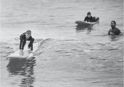  ?? KRISTEN ZEIS/STAFF ?? Bryan Rogers, 8, of Richmond, catches a wave during a surf lesson hosted by the Wounded Warrior Project and taught by VB Surf Sessions at Croatan Beach in Virginia Beach on Friday.