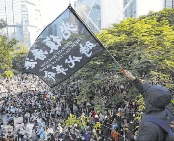  ?? Ng Han Guan The Associated Press ?? A protester waves a flag reading, “Liberate Hong Kong, the revolution of our times,” during a rally Saturday by pro-democracy demonstrat­ors in Hong Kong.