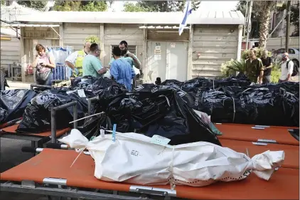  ?? GIDEON MARKOWICZ — THE ASSOCIATED PRESS ?? Forensic experts stand next to the bodies of Israelis killed by Hamas militants in the National Center for Forensic Medicine in Tel Aviv Monday.