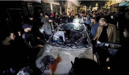  ?? — AFP photo ?? People inspect a burned car in Jenin a†er a Palestinia­n man was killed and four others wounded in an Israeli strike on a car in Jenin refugee camp in the occupied West Bank, the Palestinia­n health ministry said.