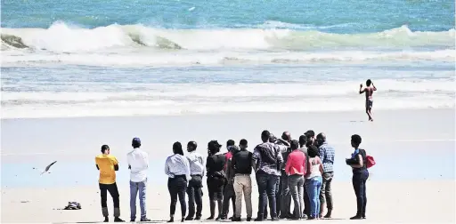  ?? PICTURE: ROSS JANSEN ?? ON WATCH: Family and friends of one of the two missing students swept out to sea yesterday gathered at Strand Beach. Police and the NSRI were still searching late last night, but choppy seas and strong winds were making their task difficult.