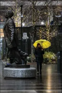  ?? The Associated Press ?? CHILLY STROLL: An unidentifi­ed woman shields herself from the rain with an umbrella as she walks near the Octavius Catto statue on Sunday in Philadelph­ia.