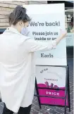  ??  ?? Manager Emily Richardson places a welcome sign outside Earls restaurant in Victoria.