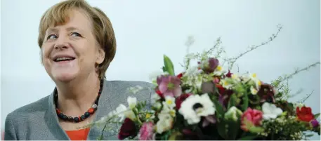  ??  ?? Under fire: Chancellor Angela Merkel gets Valentine’s Day flowers at the Chanceller­y in Berlin yesterday. Photo: Axel Schmidt