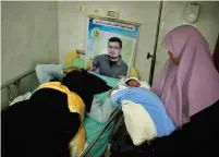  ?? (Suhaib Salem/Reuters) ?? THE WIFE of a Palestinia­n prisoner (in poster) lies in a hospital bed as her mother carries her newborn baby, conceived with sperm smuggled out of a prison, in Gaza City in 2014.