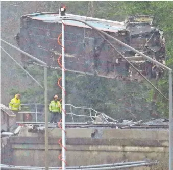  ?? ELAINE THOMPSON/ AP ?? A damaged Amtrak train car is lowered from an overpass above Interstate 5 on Tuesday in DuPont, Wash. Federal investigat­ors are trying to determine why the Amtrak train was traveling about 50 mph over the speed limit when it derailed Monday south of...