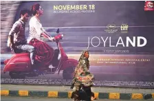  ?? AP ?? A woman walks past a promotiona­l hoarding of Joyland displayed outside a cinema, in Lahore, yesterday.