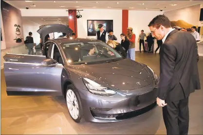  ?? ETHAN BARON — STAFF ?? Curious consumers get their first glimpse at the Tesla Model 3, the electric sedan’s first appearance in a Tesla showroom, on Friday at Stanford Shopping Center in Palo Alto. The much-anticipate­d Model 3 starts at $35,000.