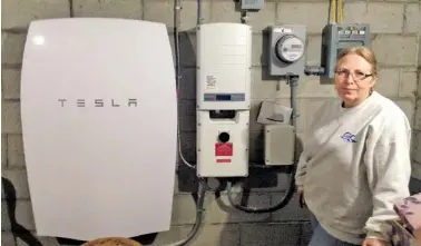  ?? THE ASSOCIATED PRESS ?? Rhonda Phillips shows off a Tesla Powerwall battery and inverter connected to a solar panel array in her yard in Middletown Springs, Vt.