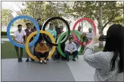  ?? GREGORIO BORGIA — THE ASSOCIATED PRESS ?? A group of students from Uruguay pose for a souvenir picture on the Olympic Rings set outside the Olympic Stadium in Tokyo, Saturday, March 21, 2020. The Olympic flame from Greece arrived in Japan Friday, even as the opening of the the Tokyo Games in four months is in doubt with more voices suggesting the games should to be postponed or canceled because of the worldwide virus pandemic.