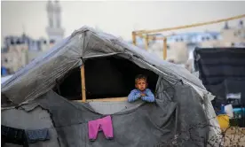  ?? Photograph: AFP/Getty Images ?? A Palestinia­n child looks out of a tent in a displaceme­nt camp in Rafah, in the southern Gaza Strip, 13 May 2024.