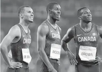  ??  ?? Canada’s Andre De Grasse, left, Brendon Rodney and Aaron Brown watch the scoreboard after the men’s 4x100-metre relay final in Rio on Friday.