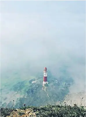  ??  ?? Beachy Head lighthouse is surrounded by eerie mist. Doctors in protective suits, left, treated people falling ill