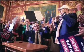  ?? (AP/Wisconsin State Journal/John Hart) ?? Wisconsin Gov. Tony Evers raises a bill which re-defines the state’s legislativ­e maps after signing it at the Wisconsin State Capitol in Madison, Wis., on Monday.