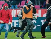  ?? FOTO: DPA ?? Kriminelle auf dem Rasen: Vermummte aus dem Lager des 1. FC Köln haben beim Derby gegen Mönchengla­dbach eine Fahne geklaut.