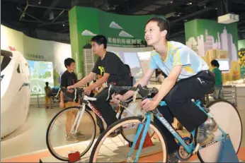  ?? PHOTOS PROVIDED TO CHINA DAILY ?? Top: Children learn about wind power by watching a simulated sailing ship movement at the Hangzhou Low Carbon Science and Technology Museum. Above: Visitors cycle to measure their carbon discharge at the Low-carbon City section of the museum.