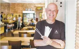  ?? BRIAN CASSELLA/FOR THE BALTIMORE SUN ?? Ned Atwater, the owner of Atwater’s restaurant­s and carry-outs, with paper straws, which the chain substitute­d for plastic about two months ago.