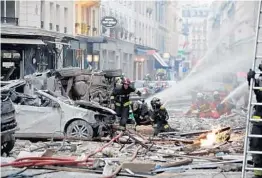  ?? THOMAS SAMSON/GETTY-AFP ?? Firefighte­rs work the scene after the explosion at a bakery Saturday on a corner in central Paris. Authoritie­s said 200 firefighte­rs and police were involved in the operation.