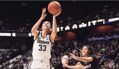  ?? Jessica Hill / Associated Press ?? UConn’s Caroline Ducharme (33) shoots over Louisville’s Chelsie Hall (23) on Sunday. The Cardinals rose to No. 3 in the AP Top 25 after defeating UConn, while the Huskies fell to No. 11.