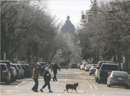  ?? KAYLE NEIS ?? The Saskatchew­an Legislativ­e Building peaks out from the trees as pedestrian­s cross Smith Street on Friday. The City of Regina is looking at a second phase of zoning bylaw changes to incentiviz­e housing diversity, this time allowing six-storey buildings as-of-right.