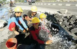  ?? RIANA SETYAWAN/JAWA POS ?? DERAS: Petugas PDAM menyelesai­kan perbaikan pipa yang bocor di Jalan Tambak Langon, Surabaya, kemarin.