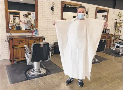  ?? Photos by Lori Van Buren / Times Union ?? Joey Federico, owner of The Barber Parlor in Albany, holds a disposable cape that customers will wear as he prepares on Tuesday to reopen. Barber shops are among businesses allowed to reopen Wednesday.