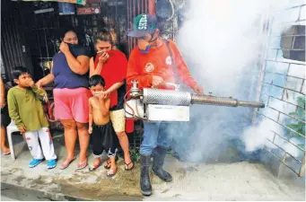  ??  ?? DENGUE PREVENTION – As a family looks on, a worker uses a defogging machine to eliminate adult mosquitoes, which could be the source of the dengue virus in this community on Sto. Niño St. in Barangary 177, Maligaya, Caloocan City. (Mark Balmores)