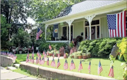  ?? / Spencer Lahr ?? A home at 209 E. Fourth St. sports dozens of small flags outlining the yard and walkway along with a larger American flag and a 1st Infantry Division flag the day before Independen­ce Day.