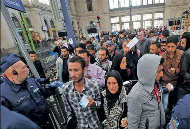  ??  ?? Agentes de policía revisan en Budapest los billetes de un grupo de refugiados a punto de subir a un tren hacia la frontera austriaca