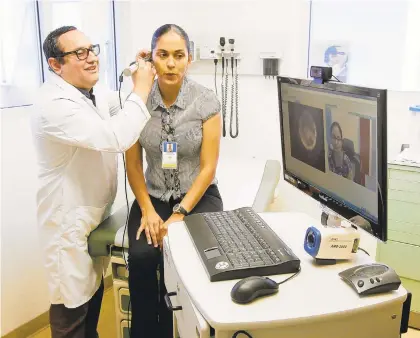  ?? EDUARDO CONTRERAS/SAN DIEGO UNION-TRIBUNE 2017 ?? Dr. Javier Rodriguez, quality improvemen­t director Sonia Tucker, and quality improvemen­t specialist Navjot Gill (on computer screen at right), demonstrat­e one of the uses (ear exam) of a telemedici­ne cart at the La Maestra Community Health Centers Women’s Clinic in San Diego in 2017. Devices such as this allow doctors to see patients without having to be in the same physical space.