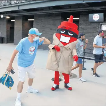  ?? CHRIS SWEDA/CHICAGO TRIBUNE ?? A Chicago Dogs fans elbows the Ketchup mascot at the home opener for the Dogs’ at Impact Field in Rosemont on July 7.