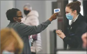  ?? (File Photo/AP/Robert F. Bukaty) ?? Darmita Wilson (left) takes the temperatur­e of a volunteer arriving March 2 to help at a covid-19 mass vaccinatio­n site at the Portland Expo in Portland, Maine.