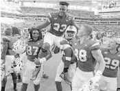  ?? AL DIAZ/TNS ?? Hurricanes teammates carry tight end Christophe­r Herndon IV off the field after Saturday’s win over Virginia.