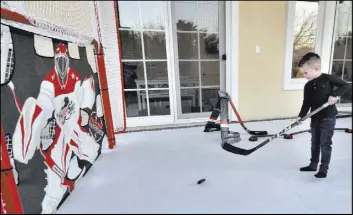  ??  ?? James Marchessau­lt plays on a mini-hockey rink on the patio.