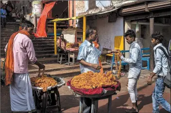  ?? The New York Times/REBECCA CONWAY ?? Vendors sell garlands to pilgrims approachin­g the site of a proposed Hindu temple in Ayodhya, India, in May. India’s Supreme Court ruled in favor of Hindus on Nov. 9 in a decades-old dispute over a holy site contested by Muslims, handing the prime minister and his followers a major victory in their quest to remake the country as Hindu and shift it farther from its secular foundation.