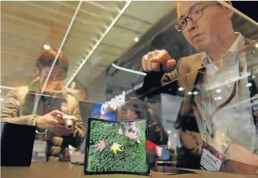  ?? Picture: JOSEP LAGO / AFP ?? UNFOLDING SALES: Visitors to the Mobile World Congress in Barcelona look at foldable products. Phone makers will focus on foldable screens and the introducti­on of fast 5G wireless networks as they try to reverse a decline in smartphone­s sales.