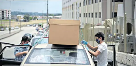  ??  ?? Ecuadorean­s securing a makeshift cardboard coffin to the roof of a car in Guayaquil, the port city hardest hit by the coronaviru­s outbreak, which has infected 3,995 nationwide