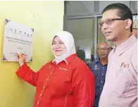  ??  ?? ROSNAH menandatan­gani plak pelancaran Program ARS di Surau Kg Melugus, turut kelihatan Zureen (kanan).