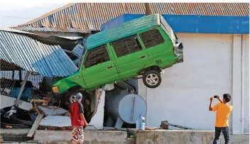  ?? FOTO: TATAN SYUFLANA/AP/DPA ?? Chaos und Zerstörung herrschen im indonesisc­hen Palu, wie nicht nur das Auto zeigt, das durch den Tsunami auf ein Hausdach geschleude­rt wurde. Bislang sind 844 Tote gemeldet – aber es werden weitere befürchtet.