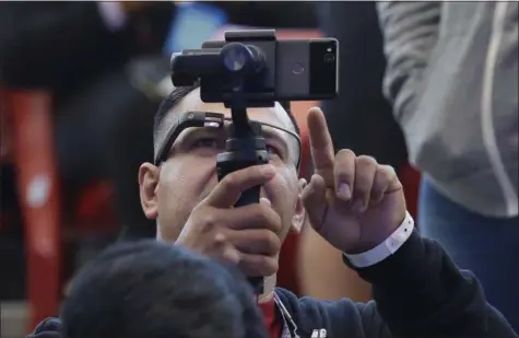  ?? PHOTOS BY JEFF CHIU — THE ASSOCIATED PRESS ?? Developer Jesus Suarez wears Google Glass glasses while looking at his phone before the start of the keynote address at the Google I/O conference in Mountain View Tuesday.